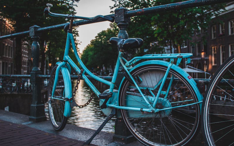 A blue bicycle beside a leafy canal